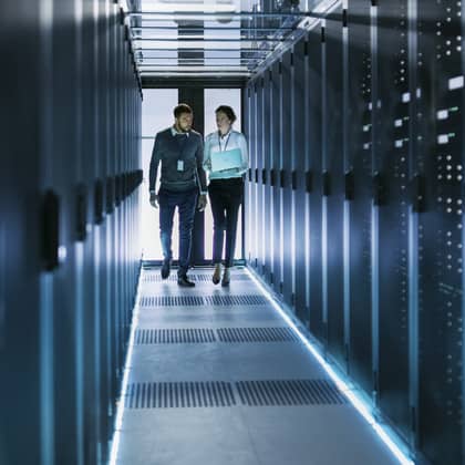 Two people walking across a server room